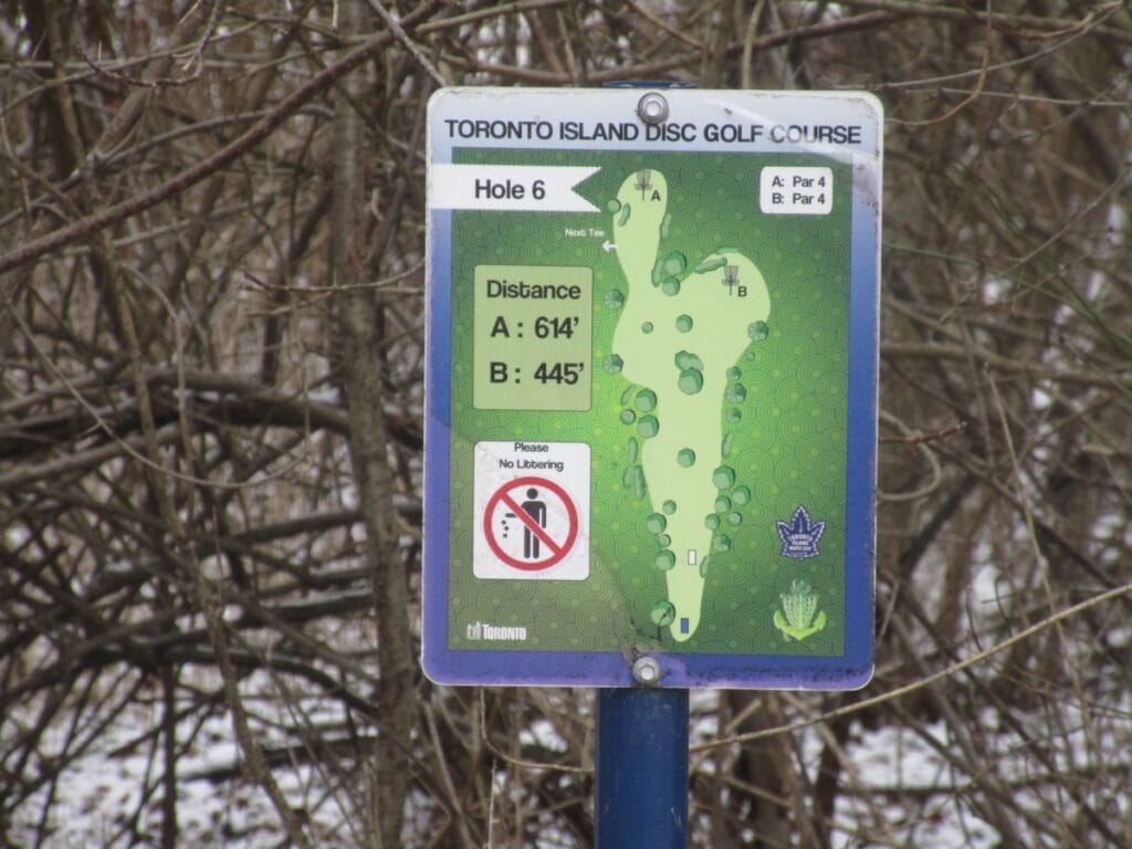 Informational sign for Hole 6 at the Toronto Island Disc Golf Course, displaying distances for tee positions A and B, a map of the hole layout with a par of 4, and a 'No Littering' icon